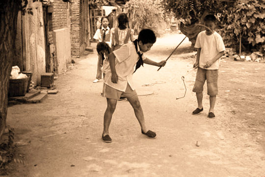 老照片：在村路口边抽陀螺的小孩