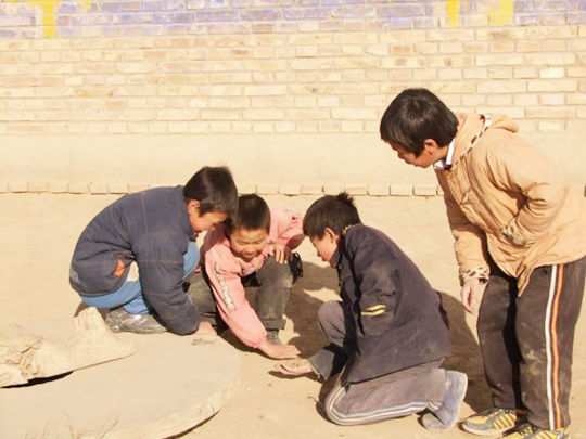 跪在乡村土路上弹杏仁的四个小孩